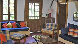 Un salon chaleureux avec un canapé bleu, des fauteuils à motifs et une table basse.