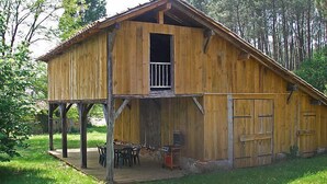Une cabane en bois rustique dotée d’un balcon, d’une véranda avec des chaises et d’une petite table.