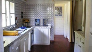Une cuisine compacte avec des meubles blancs, un four encastré, un évier et une fenêtre.