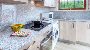 Une cuisine moderne dotée de plans de travail en granit, d’un four à micro-ondes, d’une cuisinière et d’un lave-linge.