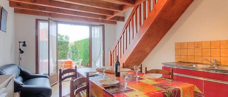 A dining area with a table set for two, a staircase, and a kitchen area.