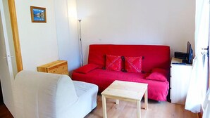 A small, bright room with a red sofa, a white armchair, and a wooden table. - L'Enclave I et J by Interhome (Les Contamines)