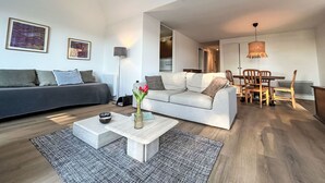 Ein modernes Wohnzimmer mit einer Couch, einem Couchtisch und einem Essbereich mit Stühlen und einem Tisch.