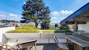 Eine Dachterrasse mit Blick auf einen Yachthafen, einen großen Baum und Sitzgelegenheiten im Freien.