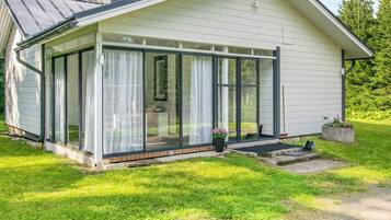 A modern house with a glass-enclosed porch, a chimney, and a well-maintained lawn.