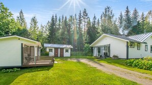 Une rangée de maisons mobiles, avec une pelouse et une forêt en arrière-plan.