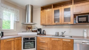 Une cuisine moderne avec des meubles en bois, des appareils électroménagers en acier inoxydable et une fenêtre donnant sur un paysage verdoyant.