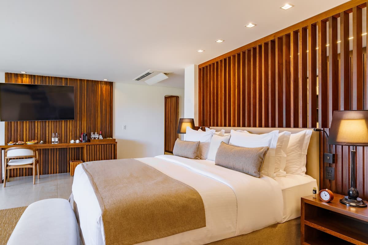 Une chambre d’hôtel moderne dotée d’un grand lit, d’un bureau avec un téléviseur à écran plat et d’une tête de lit en bois.