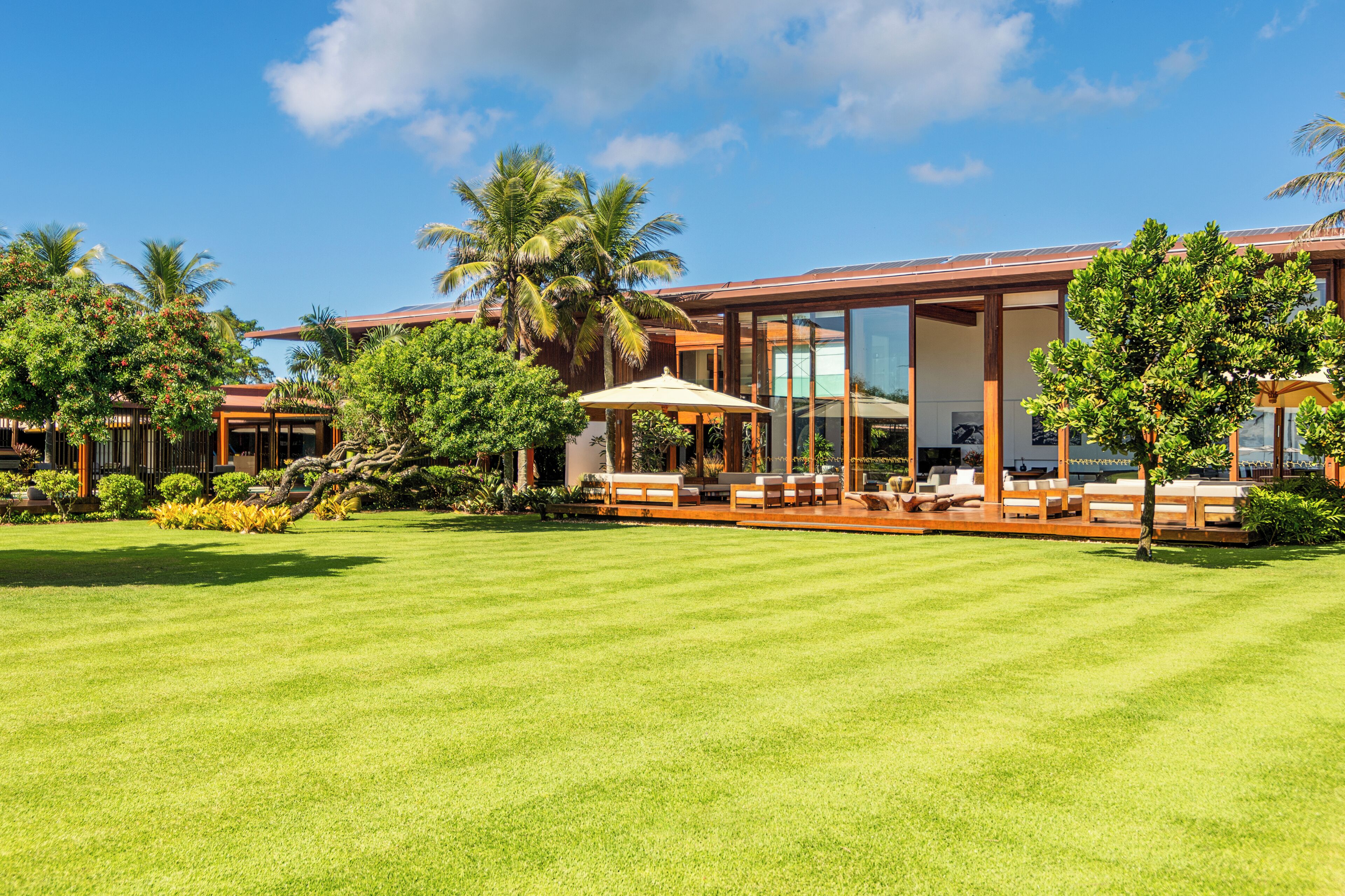 Un resort moderno con césped bien cuidado, zonas de estar al aire libre y jardines tropicales.