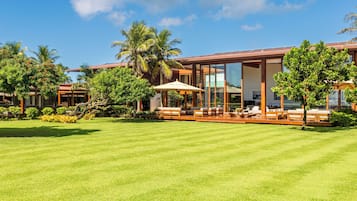 Ein modernes Resort mit gepflegter Rasenfläche, Sitzbereichen im Freien und tropischer Bepflanzung.