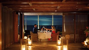 A romantic outdoor dining setup with a view of the ocean at night. - Zendaya Resort Beach Sport & Spa (Búzios)
