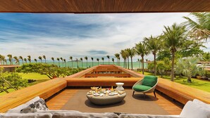 A deck with a wooden bench, a round table with food and drinks, and a green chair. - Zendaya Resort Beach Sport & Spa (Búzios)