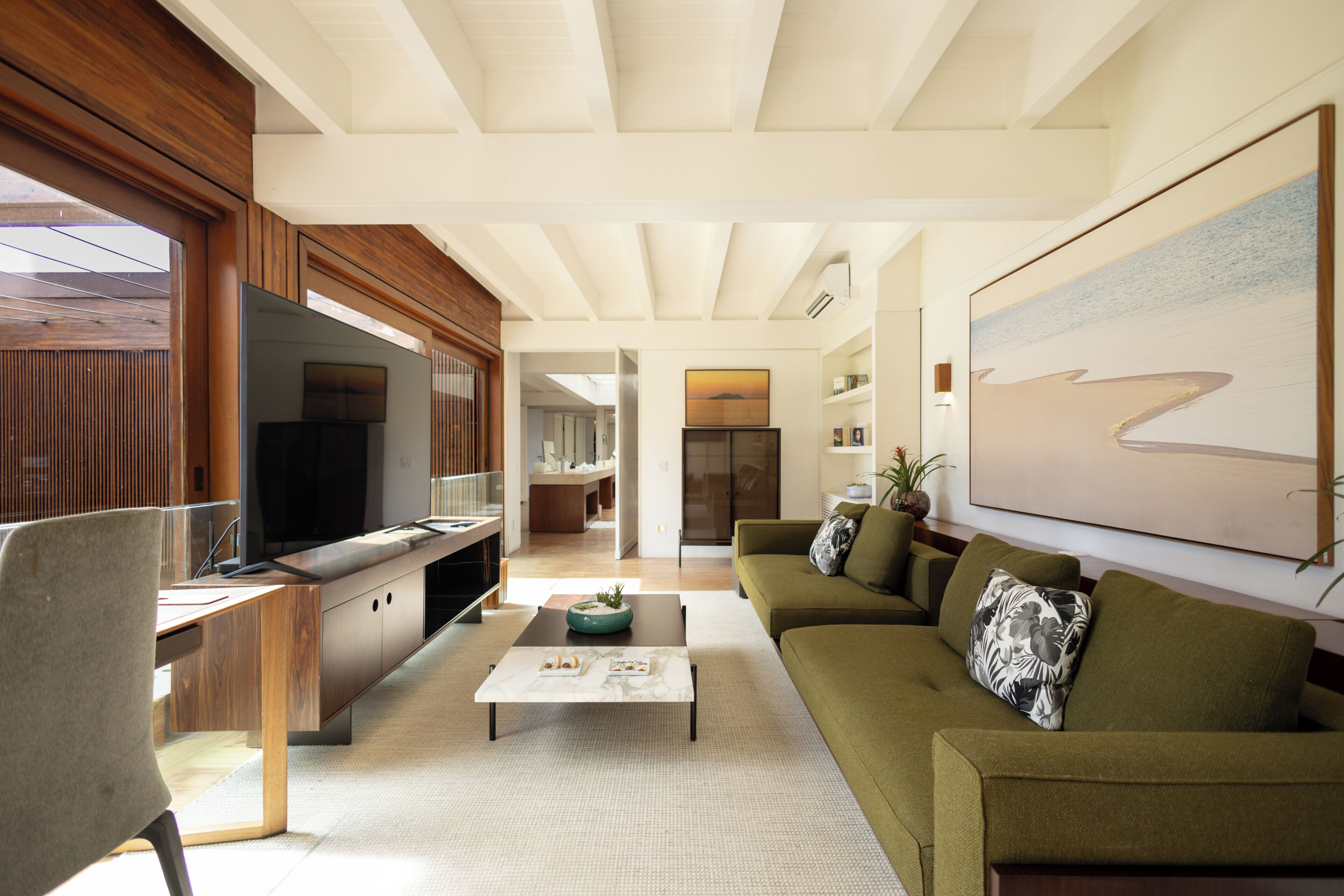 Uma sala de estar moderna com sofá, mesa de centro, televisão e painéis de madeira.