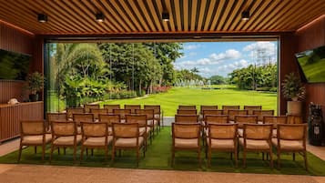 Una habitación con vistas a un campo de golf, paneles de madera y sillas de mimbre.