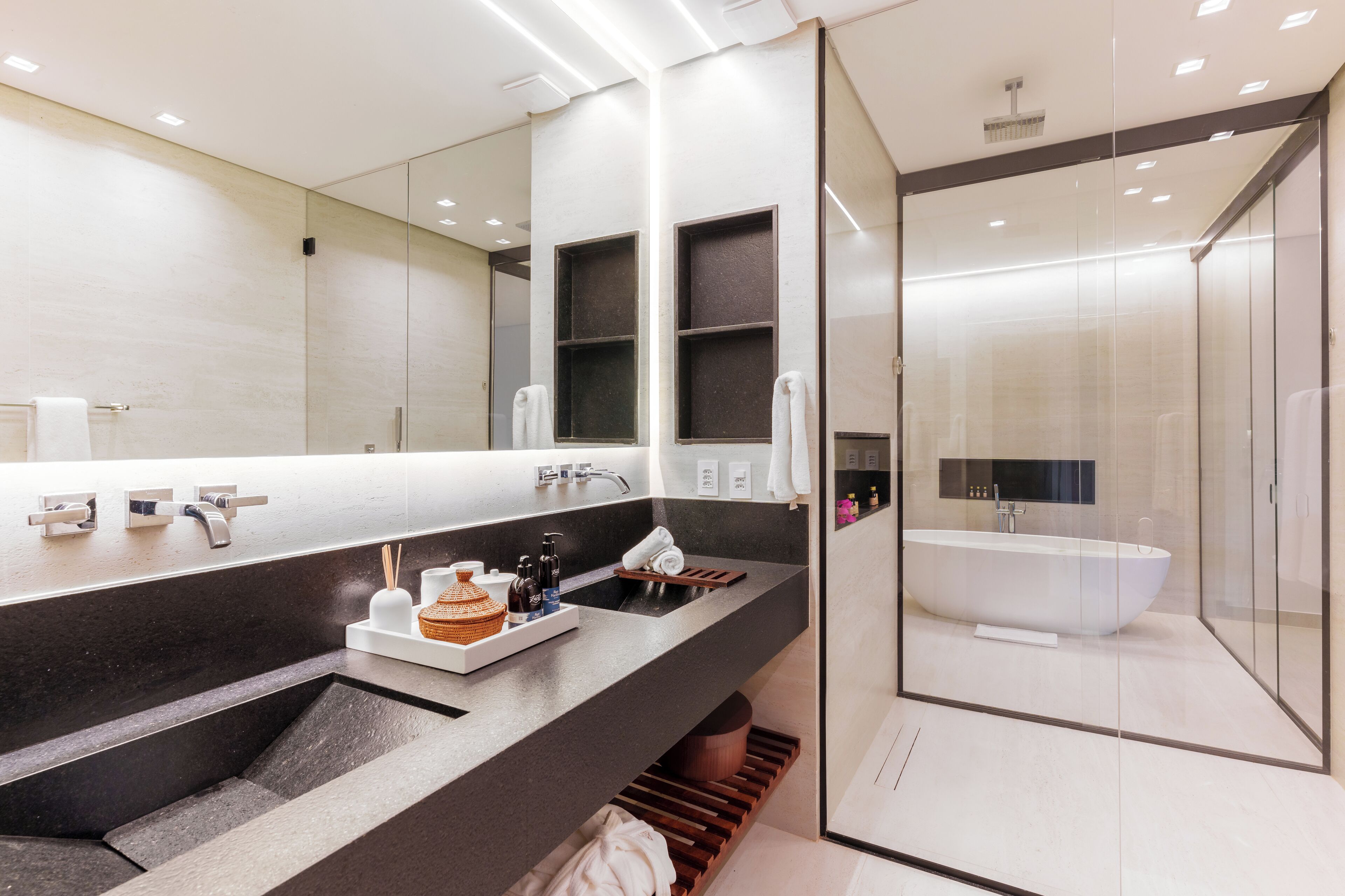 A modern bathroom with a large mirror, a freestanding bathtub, and a dual sink vanity.