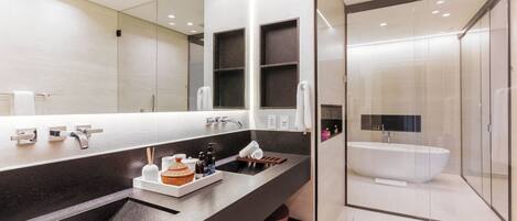 A modern bathroom with a large mirror, a freestanding bathtub, and a dual sink vanity.