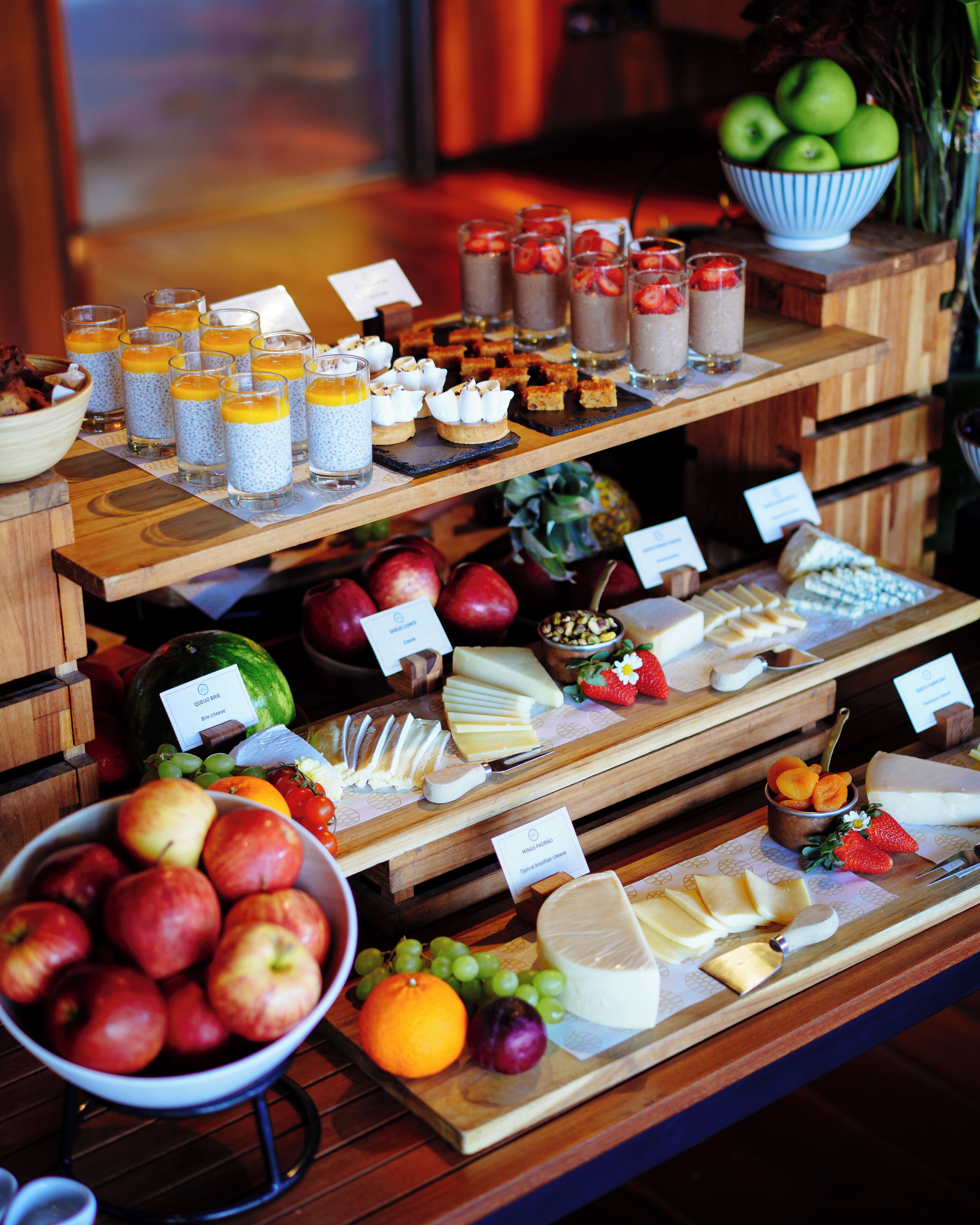 A buffet with various food items including fruits, cheeses, and desserts.