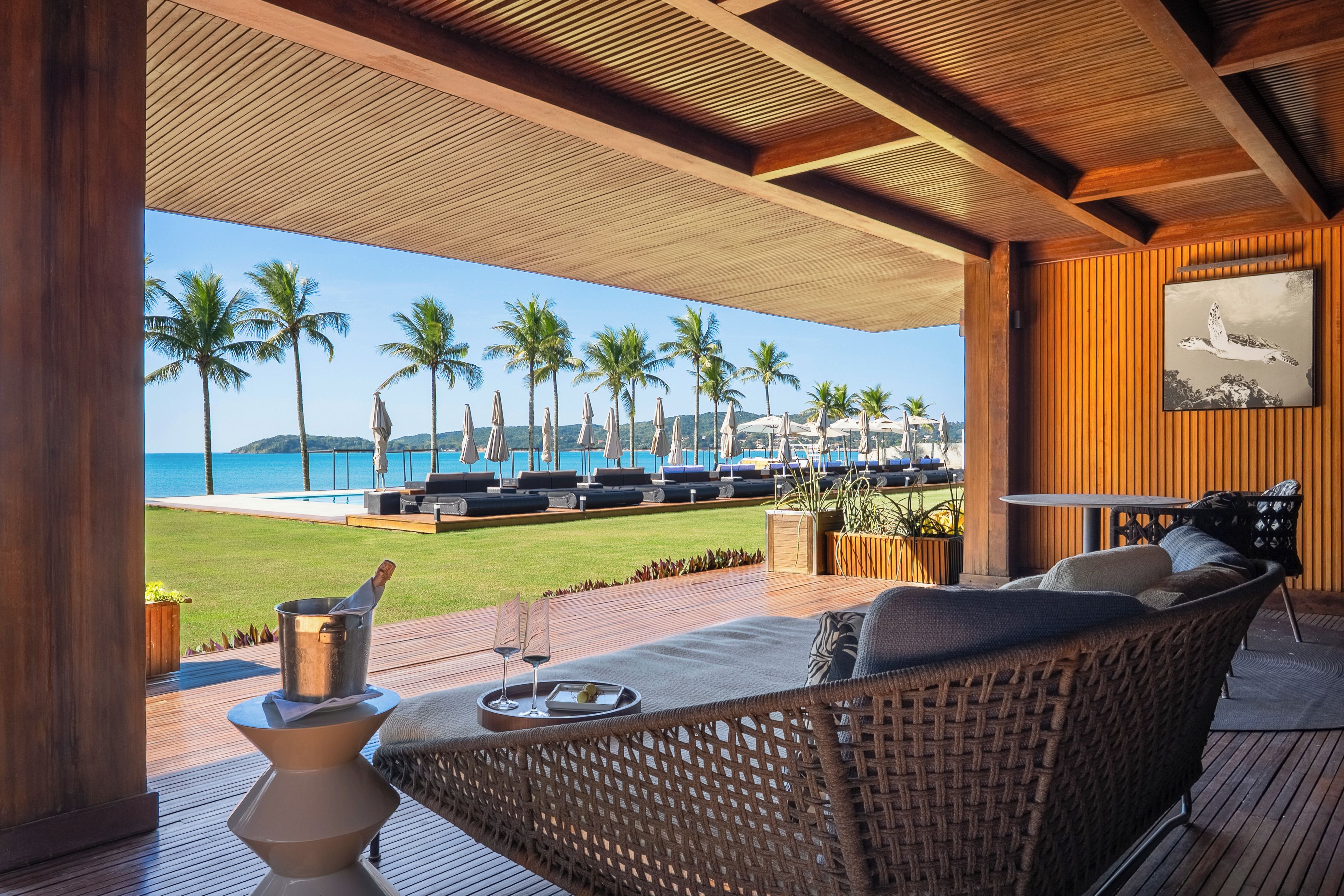 Ein Loungebereich mit Blick auf das Meer, Palmen und einen Pool.