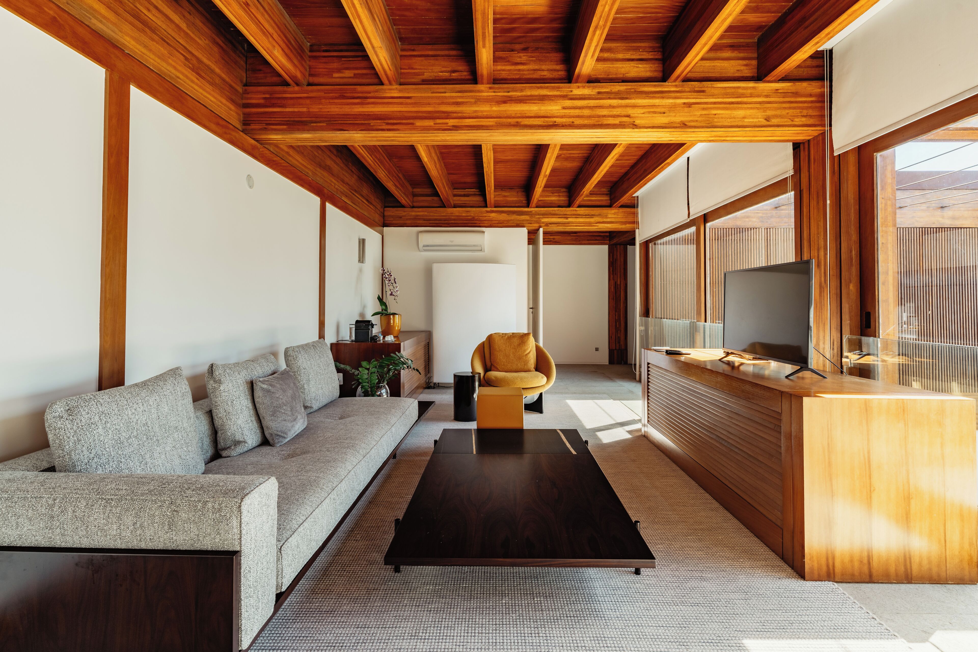 A modern living room with a wooden ceiling, a sofa, a coffee table, and a TV.