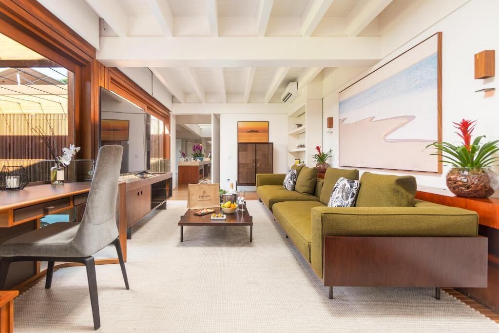 A modern living room with a sofa, a coffee table, and a chair. There is a television and a large painting on the wall.