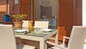 A dining area with a glass table, wicker chairs, and a potted plant. - Marcella by Interhome (Forte dei Marmi)