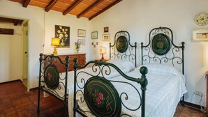A bedroom with a wooden ceiling, a bed with ornate metal headboard, a bedside table, and a lamp. - La Capannella by Interhome (Camaiore)