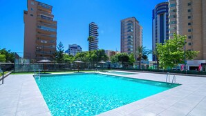 A swimming pool with clear blue water, surrounded by a tiled deck, and tall buildings in the background. - Mirador de Calpe by Interhome (Calpe/Calp)