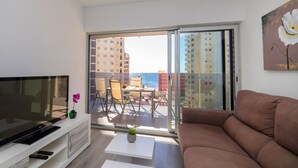 A modern living room with a flat-screen TV, a sofa, a coffee table, and a balcony with a view of the sea and buildings. - Mirador de Calpe by Interhome (Calpe/Calp)