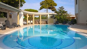 En pool med solstolar och ett avskärmat område med sittplatser.