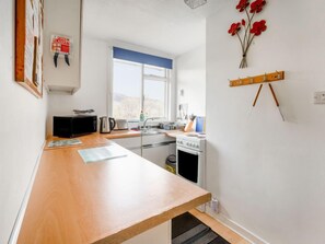 A kitchen with a wooden countertop, a stove, a sink, and a window.