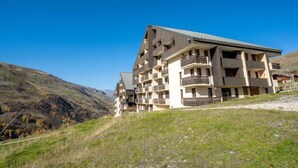 Ein mehrstöckiges Hotel mit modernem architektonischen Design, gelegen in einer hügeligen Landschaft unter blauem Himmel.