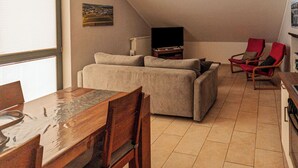 En hyggelig stue med en sofa, et fjernsyn og et spisebord med stole.