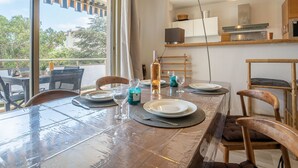 Een eetruimte met een grote tafel, stoelen en uitzicht op de omgeving.