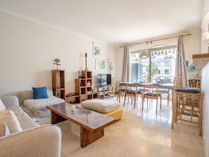 Una sala de estar moderna con un sofá, una mesa de centro, un televisor y un comedor con sillas y una mesa.