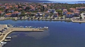 Eine Küstenstadt mit einem Jachthafen, Häusern mit roten Dächern und freiem Blick auf das Meer.
