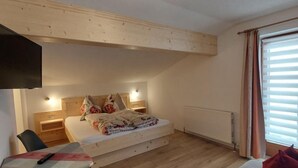 Une chambre avec un lit en mezzanine, une petite table, une chaise et un canapé.