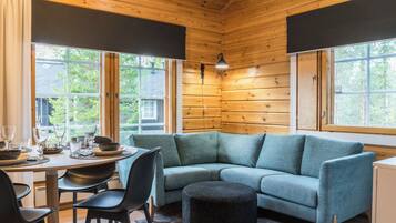 Een knus chaletinterieur met een eethoek, een bank en een rond poef.