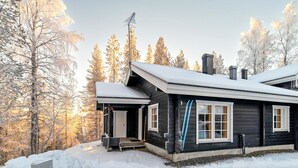 A cabin with a porch, a chimney, and a snow-covered landscape.