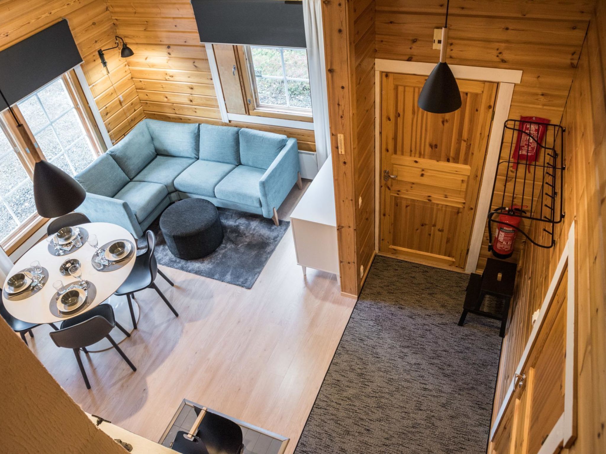 A modern log cabin interior with a sectional sofa, dining table, and chairs.