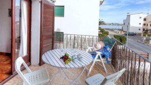 A balcony with a round table, white chairs, and a view of the sea. - Sant Carles by Interhome (Llançà)