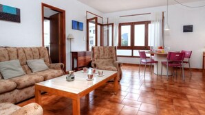 A living room with a sofa, armchairs, a wooden coffee table, and a dining area with a table and chairs. - Sant Carles by Interhome (Llançà)
