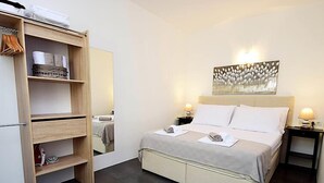 Une chambre bien rangée, avec un lit, une armoire et un miroir.