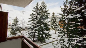 Un balcon d’où l’on peut admirer des arbres couverts de neige et une montagne en arrière-plan.