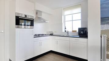 Een koelkast, een vaatwasser, kookgerei, borden en bestek