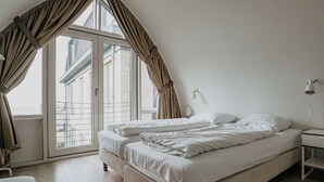 Un dormitorio con una cama grande, una mesita de noche, una lámpara y vistas a través de un ventanal corredizo.