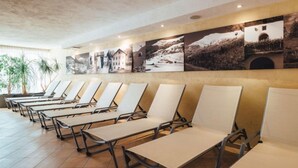 Un hall d’hôtel avec des rangées de chaises longues et un mur décoré de photographies de paysages.