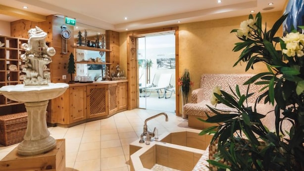 Un intérieur moderne avec un comptoir d’accueil en bois, une fontaine en pierre et un espace détente agrémenté d’un canapé à motifs.