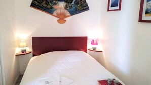 A hotel room with a bed, two bedside lamps, a wall-mounted fan, and framed pictures. - Hego Alde by Interhome (Bidart)