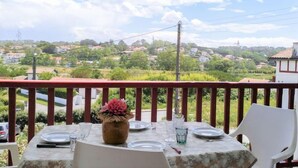 A table set for two with a vase of flowers, a clear sky, and a view of a residential area. - Hego Alde by Interhome (Bidart)