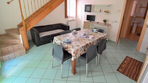 A dining area with a table set for four, a sofa, a TV, and a staircase. - Solmare by Interhome (Rosolina Mare)